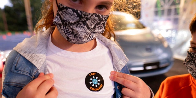 Leah Lefkove, 9, shows off her vaccination sticker just before being the first child to be vaccinated at the Viral Solutions vaccination and testing site in Decatur, Ga., on the first day COVID-19 vaccinations were available for children from 5 to 12 on Wednesday, Nov. 3, 2021. (AP Photo/Ben Gray)