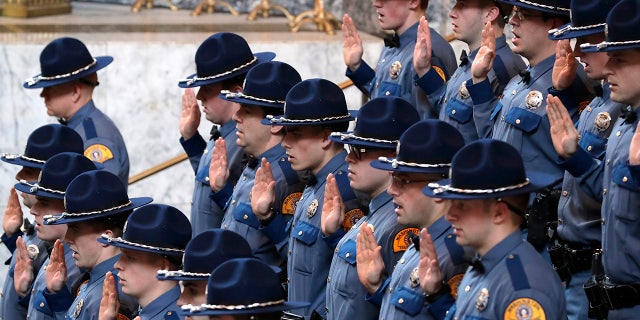 New Washington State Patrol troopers taking part in a graduation ceremony raise their right hands and take the Oath of Office, Thursday, Dec. 13, 2018, in the Rotunda at the Capitol in Olympia, Wash.