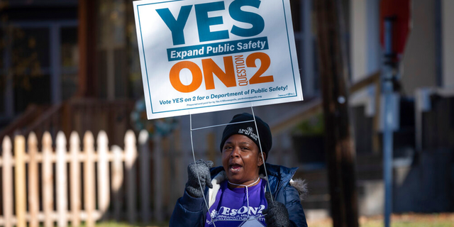 A volunteer urges community members to vote yes on ballot question two outside of a polling place on Tuesday, Nov. 2, 2021 in Minneapolis.