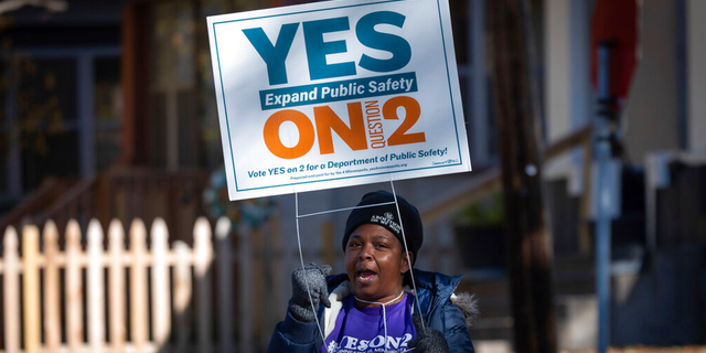 A volunteer urges community members to vote yes on ballot question two outside of a polling place on Tuesday, Nov. 2, 2021 in Minneapolis.