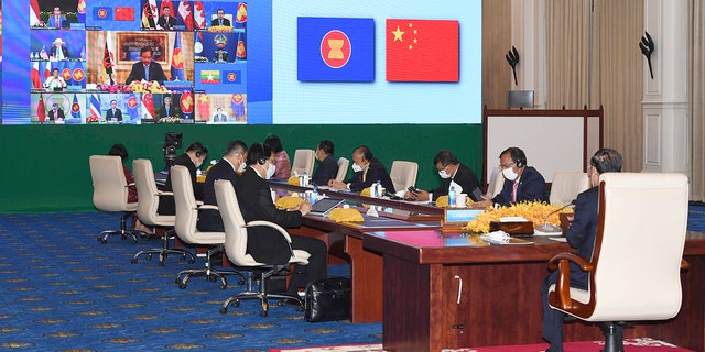 In this photo provided by the An Khoun Sam Aun/National Television of Cambodia, Cambodian Prime Minister, right, joins an online meeting of the ASEAN-China special summit at Peace Palace in Phnom Penh, Cambodia, Monday, Nov. 22, 2021. 