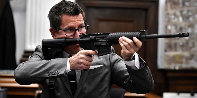 Assistant District Attorney Thomas Binger holds Kyle Rittenhouse's gun as he gives the state's closing argument in Kyle Rittenhouse's trial at the Kenosha County Courthouse in Kenosha, 威斯。, 在星期一, 十一月. 15, 2021.