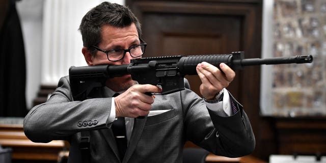 Assistant District Attorney Thomas Binger holds Kyle Rittenhouse's gun as he gives the state's closing argument in Kyle Rittenhouse's trial at the Kenosha County Courthouse in Kenosha, Wis., on Monday, Nov. 15, 2021.