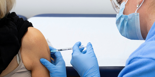 A woman receives a booster shot of Moderna's COVID-19 vaccine from a health care worker at the vaccination reference center at the Epidemiology, Biostatistics and Prevention Institute (EBPI) in Zurich, Switzerland November 17, 2021.