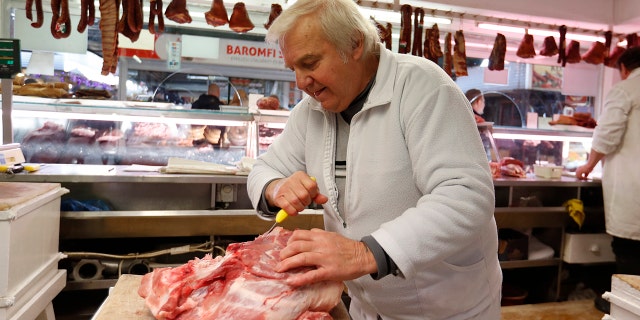 Vendor Misi Kovacs prepares the meat to sell in a food market in Budapest, Hungary, Nov. 20, 2021.