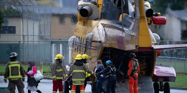Search and rescue personnel help flood evacuees disembark from a helicopter in Agassiz, British Columbia, Monday, Nov. 15, 2021.