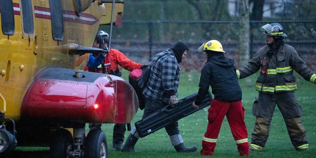 Search and rescue personnel help flood evacuees disembark from a helicopter in Agassiz, British Columbia, Monday, Nov. 15, 2021.