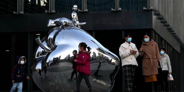 Residents wearing masks pass by artwork outside a mall in Beijing, China, on Nov. 13. 