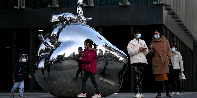 Residents wearing masks pass by artwork outside a mall in Beijing, China, on Nov. 13.