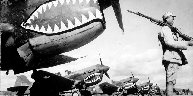 Guarded by a Chinese soldier, a squadron of Curtiss P-40 fighter planes, decorated with the typical shark face of the famed Flying Tigers, are lined up at an unknown airbase in China in 1943. 