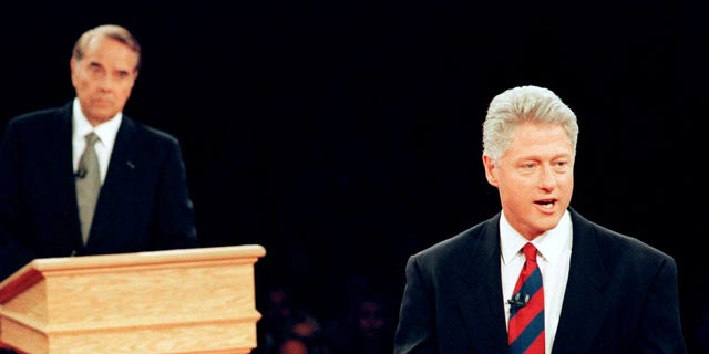 President Bill Clinton (R) strolls away from his podium to talk to the audience as Republican presidential candidate Bob Dole watches during their second and final debate in San Diego, California, U.S., October 16, 1996. REUTERS/Win McNamee/File Photo