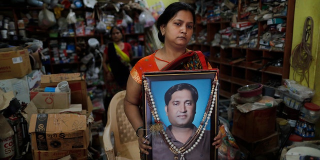 Reena Kesarwani segura uma fotografia de seu marido, Anand Babu Kesarwani, que morreu de COVID-19, em sua loja de ferragens em 25 de outubro de 2021, na vila de Chhitpalgarh, no estado de Uttar Pradesh, no norte da Índia. 