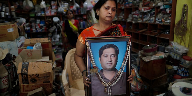 Reena Kesarwani segura uma fotografia de seu marido, Anand Babu Kesarwani, que morreu de COVID-19, em sua loja de ferragens em 25 de outubro de 2021, na vila de Chhitpalgarh, no estado de Uttar Pradesh, no norte da Índia.