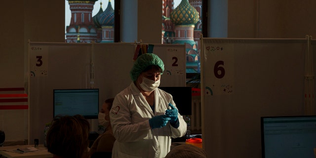 Um trabalhador médico prepara uma injeção da vacina russa contra o coronavírus Sputnik Lite em um centro de vacinação na GUM, loja do Departamento de Estado, na Praça Vermelha com a Catedral de São Basílio ao fundo em Moscou, Rússia, em 26 de outubro de 2021.