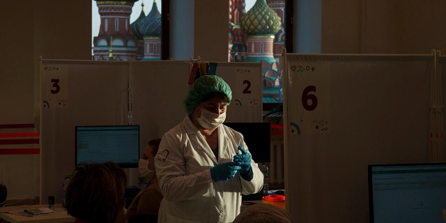 A medical worker prepares a shot of Russia's Sputnik Lite coronavirus vaccine at a vaccination center in the GUM, State Department store, in Red Square with the St. Basil Cathedral in the background in Moscow, Russia, on Oct. 26, 2021. 