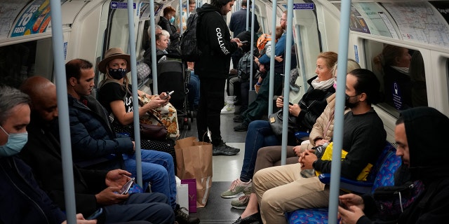 People travel on a London underground tube train on the Jubilee Line in London, Oct. 20, 2021, where face coverings are required to be worn over people's mouths and noses.