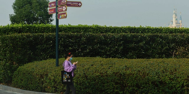 Una mujer que usa una mascarilla para ayudar a protegerse contra el coronavirus camina cerca del Shanghai Disney Resort cerrado en Shanghai, China, el lunes.