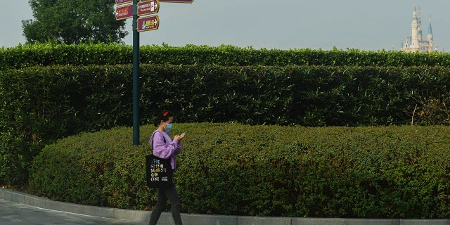 A woman wearing a face mask to help protect from the coronavirus walks near the closed Shanghai Disney Resort in Shanghai, China, on Monday.