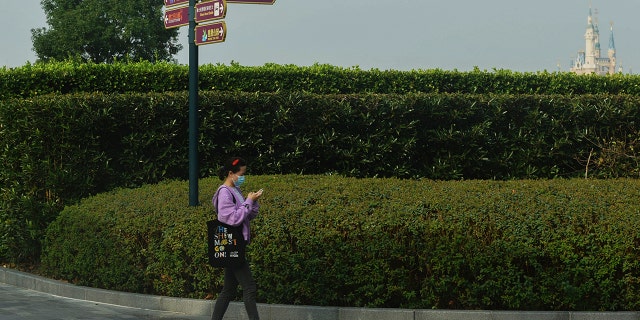 Una mujer que usa una mascarilla para ayudar a protegerse contra el coronavirus camina cerca del Shanghai Disney Resort cerrado en Shanghai, China, el lunes.