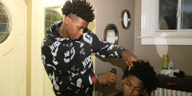 Cameron Tucker, 16, gives a haircut. The teenager was once suspended for playing bathroom barber at Renaissance High School in Detroit, Mich.