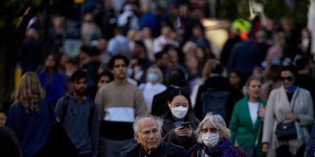 People wearing face masks walk along the Oxford Street shopping area of central London, Oct. 20, 2021.