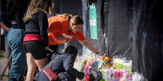 Stacey Sarmiento places flowers at a memorial in Houston on Sunday in memory of her friend, Rudy Pena, who died in a crush of people at the Astroworld music festival on Friday.