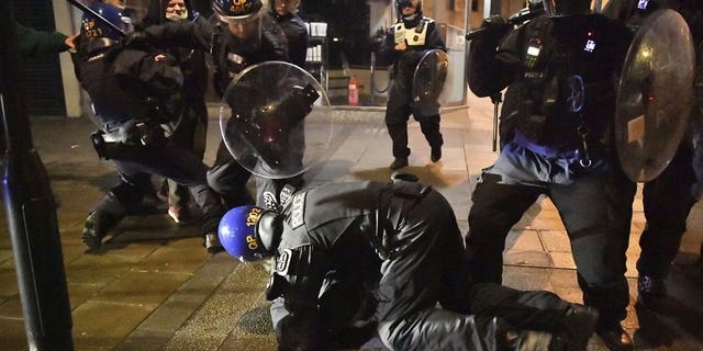 Police officers detain a man during in Bristol, England, on March 26, 2021, during a demonstration protesting new powers that would allow police to impose conditions on nonviolent protests.