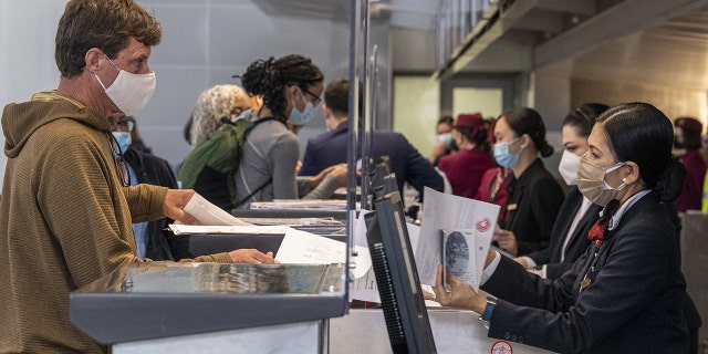 Travelers check in at the Qatar Airways check-in counter inside the international terminal at San Francisco International Airport (SFO) in San Francisco on Monday, Nov. 8, 2021. Some officials have said unvaccinated Americans should delay travel.