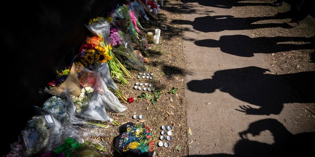 Visitors cast shadows at a memorial to the victims of the Astroworld concert in Houston on Sunday, Nov. 7, 2021.