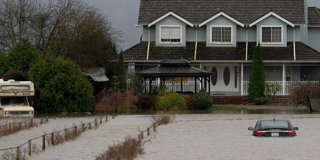 A vehicle is submerged in flood waters along a road in Abbotsford, British Columbia, Monday, Nov. 15, 2021.