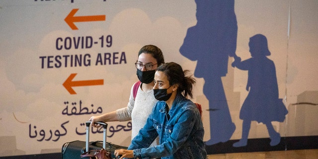 Travelers wearing protective face masks arrive at Ben Gurion Airport near Tel Aviv, Israel on Sunday, Nov. 28, 2021.
