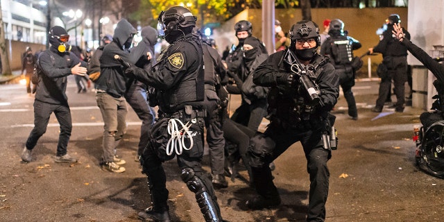 Police rush protesters at the south entrance of the Justice Center during a protest to decry the verdict in the Kyle Rittenhouse Trial. Portland, Oregon, USA, November 19th, 2021.