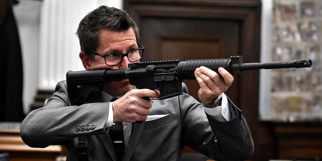 Assistant District Attorney Thomas Binger holds Kyle Rittenhouse's gun as he gives the state's closing argument in Kyle Rittenhouse's trial at the Kenosha County Courthouse in Kenosha, Wis., on Monday, Nov. 15, 2021.  (Sean Krajacic/The Kenosha News via AP, Pool)