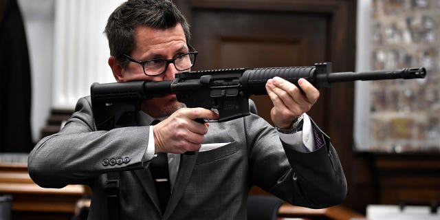 Assistant District Attorney Thomas Binger holds Kyle Rittenhouse's gun as he gives the state's closing argument in Kyle Rittenhouse's trial at the Kenosha County Courthouse in Kenosha, Wis., on Monday, Nov. 15, 2021.  Rittenhouse is accused of killing two people and wounding a third during a protest over police brutality in Kenosha, last year.  (Sean Krajacic/The Kenosha News via AP, Pool)