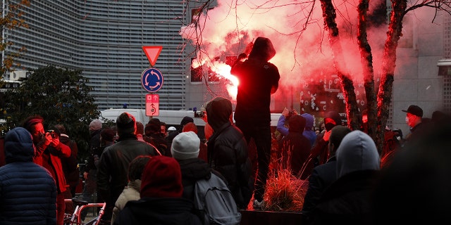 A protester lights a flare during a demonstration against the reinforced measures of the Belgium government to counter the latest spike of the coronavirus in Brussels, Belgium, Sunday, Nov. 21, 2021. 