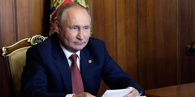 Ruský prezident Vladimir Putin se účastní zasedání Nejvyšší státní rady Státní federace Ruska a Běloruska v Den jednoty telefonicky v Sevastopolu na Krymu 4. listopadu 2021. Novinář naznačuje, že Putin byl ve skutečnosti vydírán Prezident Běloruska kvůli migrační krizi.