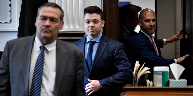 Kyle Rittenhouse, center, enters the courtroom with his attorneys Mark Richards, left, and Corey Chirafisi for a meeting called by Judge Bruce Schroeder at the Kenosha County Courthouse in Kenosha, Wis. Police departments across the country said they were ensuring the right to peaceful protests following his not guilty verdict Friday. 