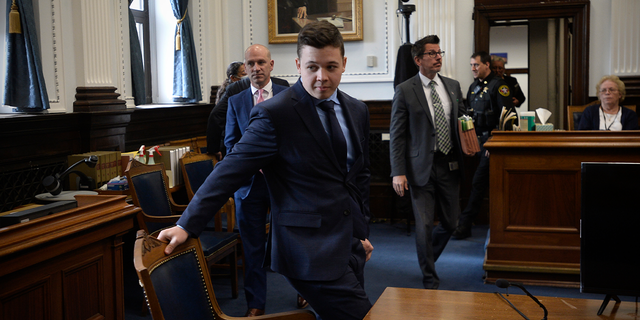 Kyle Rittenhouse, center, pulls out his chair for a meeting Judge Bruce Schroeder called during his trial at the Kenosha County Courthouse in Kenosha, Wis., on Thursday, Nov. 18, 2021. (Sean Krajacic/The Kenosha News via AP, Pool)