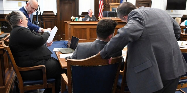 Defense attorney Mark Richards stands at right as he confers with defendant Kyle Rittenhouse, as defense attorneys Natalie Wisco, seated at left, and Corey Chirafisi also confer during a break in jury selection during Rittenhouse's trial in Kenosha, Wis., Monday, Nov. 1, 2021. (Mark Hertzberg/Pool Photo via AP)
