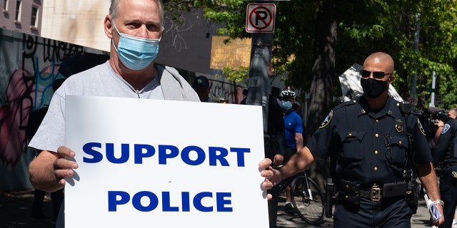 A man holds a sign during rally advocating to stop defunding of the Seattle Police Department on Aug. 9, 2020 at Seattle City Hall.