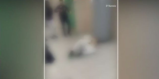 In this blurred video to protect the identities of minors, a student lies on the floor after officers appeared to pepper-spray and use a stun gun on him.