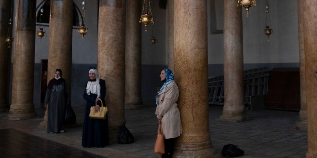 Tourists pose for a photo with renovated polished limestone columns, during a visit to the Church of the Nativity, in the West Bank city of Bethlehem, Tuesday, Nov. 16, 2021.