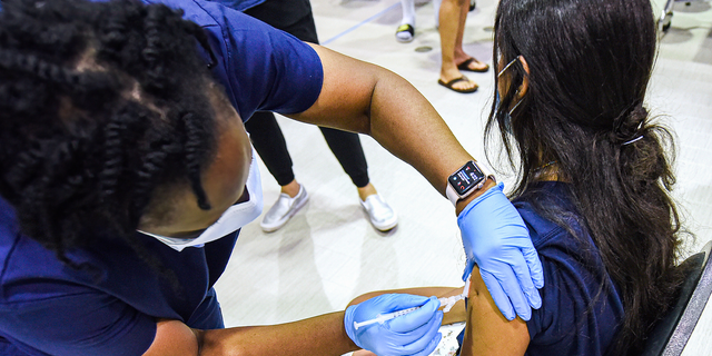 A nurse gives a girl a dose of the Pfizer vaccine at a COVID-19 vaccine clinic at Lyman High School in Longwood, Fla. 