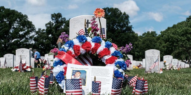 FILE – Flowers and American flags line a grave in Section 60 at Arlington National Cemetery, Virginia, U.S. May 31, 2021.