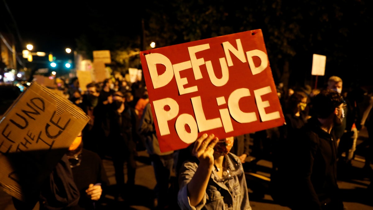 Protests carry defund the police posters during protest in New York over Daniel Prude