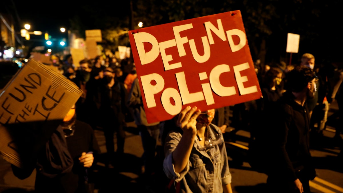 Protests carry defund the police posters during protest in New York over Daniel Prude