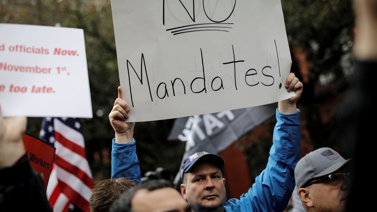 FILE PHOTO: A demonstrator holds a sign during a protest by New York City Fire Department (FDNY) union members, municipal workers and others, against the city's COVID-19 vaccine mandates on Manhattan's Upper East Side, in New York City, New York, U.S., October 28, 2021. REUTERS/Mike Segar/File Photo