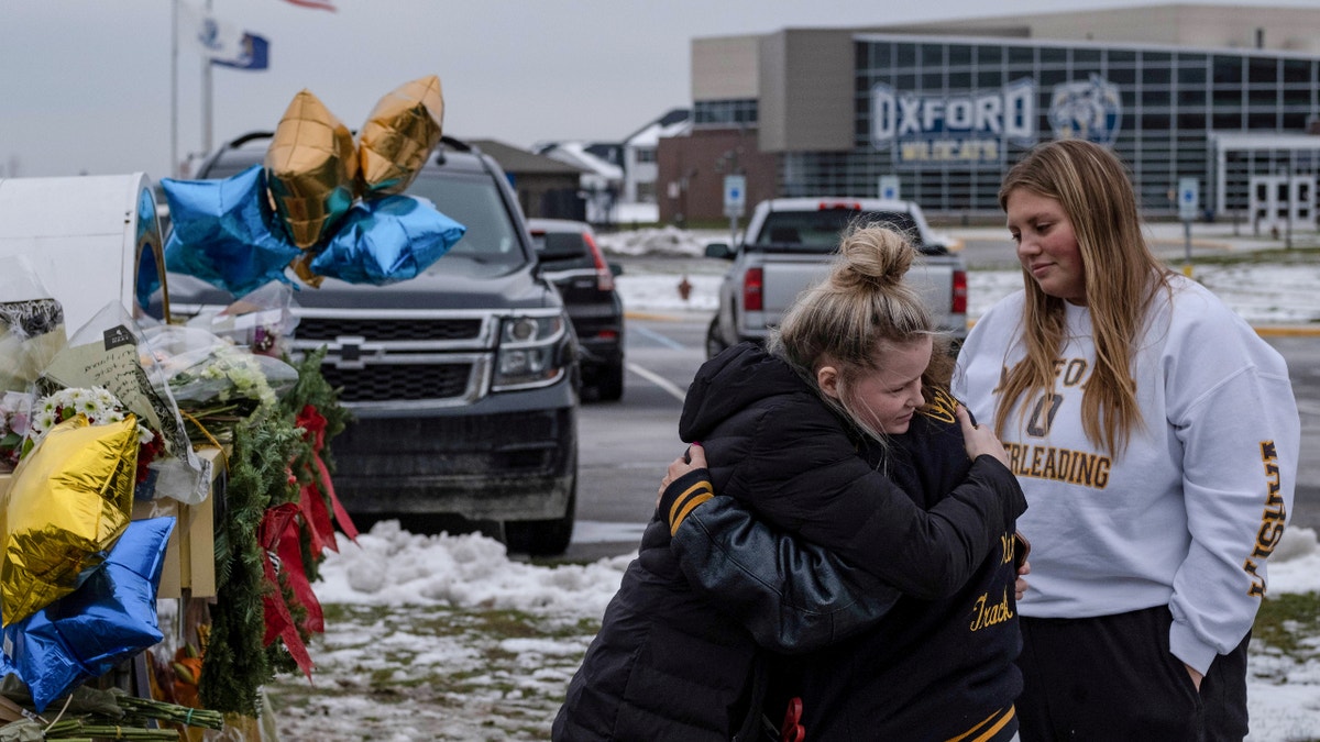 People embrace as they pay their respects at a memorial at Oxford High School, a day after a shooting that left four dead and eight injured, in Oxford, Michigan, Dec. 1, 2021. (REUTERS/Seth Herald  TPX IMAGES OF THE DAY)