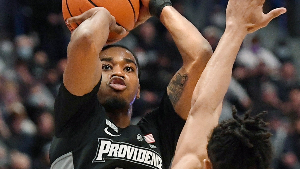 Providence's A.J. Reeves (11) makes a 3-point basket as Connecticut's Andre Jackson defends in the first half of an NCAA college basketball game, Saturday, Dec. 18, 2021, in Hartford, Conn.