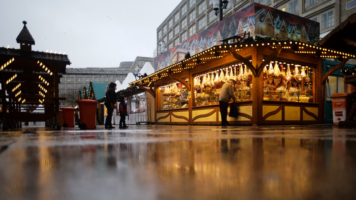 FILE - Customers wait in front of a Christmas Market on a rainy morning in central Berlin, Germany, Tuesday, Nov. 30, 2021. (AP Photo/Markus Schreiber, File)